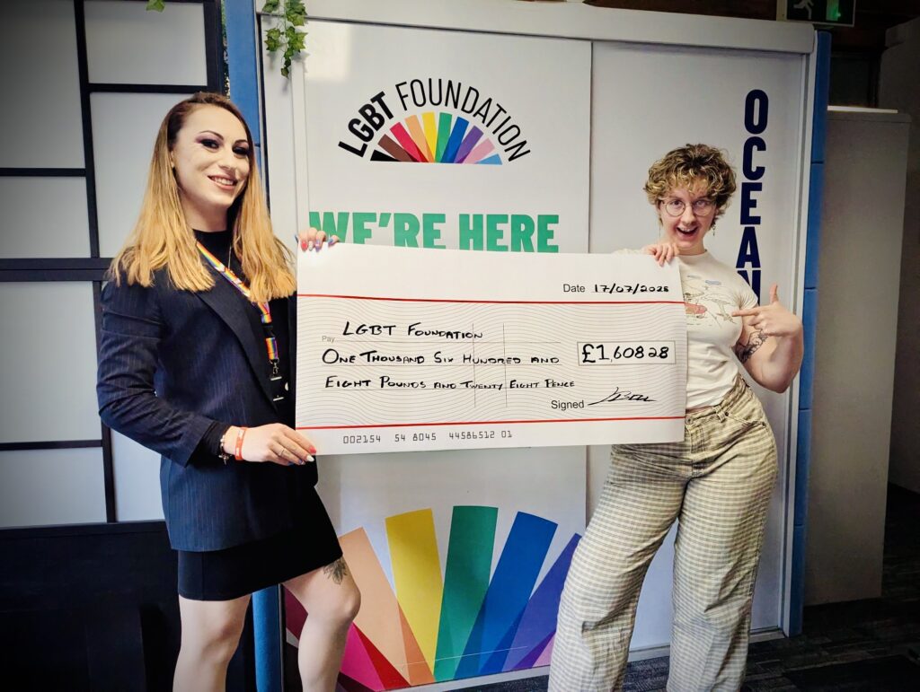Lizi Bell from IWS Water Hygiene standing with a cheque with a representative from the LGBT Foundation